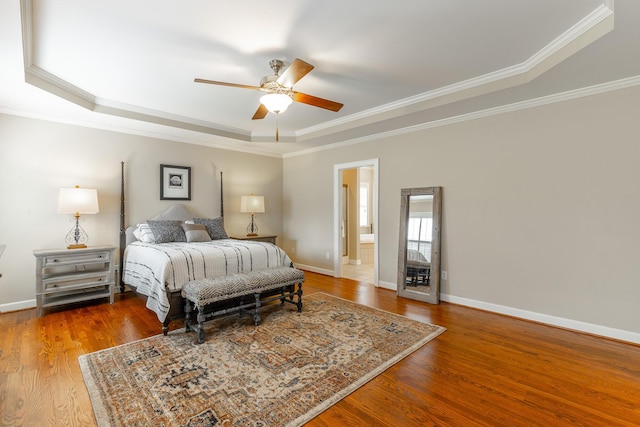 bedroom featuring a raised ceiling, baseboards, a ceiling fan, wood finished floors, and ornamental molding