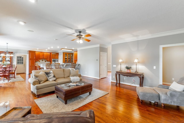 living area featuring light wood finished floors, a ceiling fan, baseboards, and ornamental molding