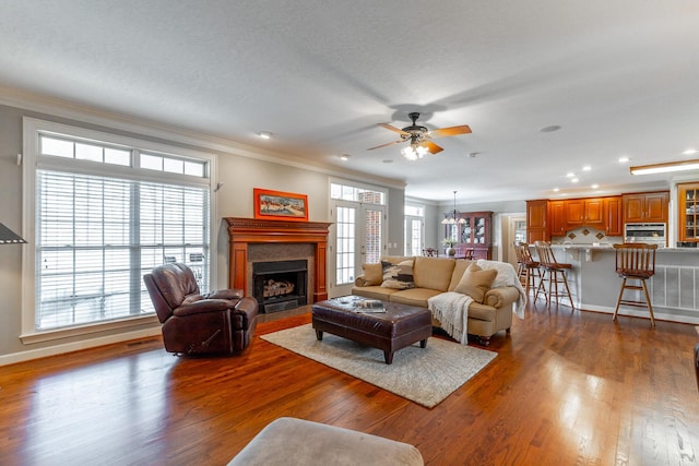 living area with a fireplace, a wealth of natural light, a ceiling fan, and ornamental molding