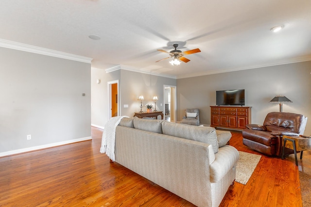 living area featuring crown molding, baseboards, a ceiling fan, and wood finished floors