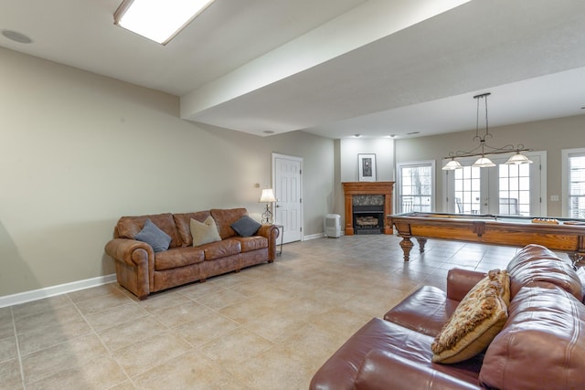 living area featuring a fireplace, baseboards, and light tile patterned floors