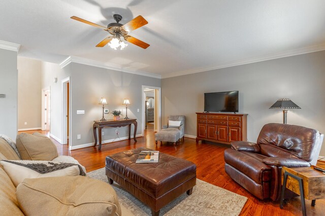 living area featuring baseboards, a ceiling fan, wood finished floors, and ornamental molding