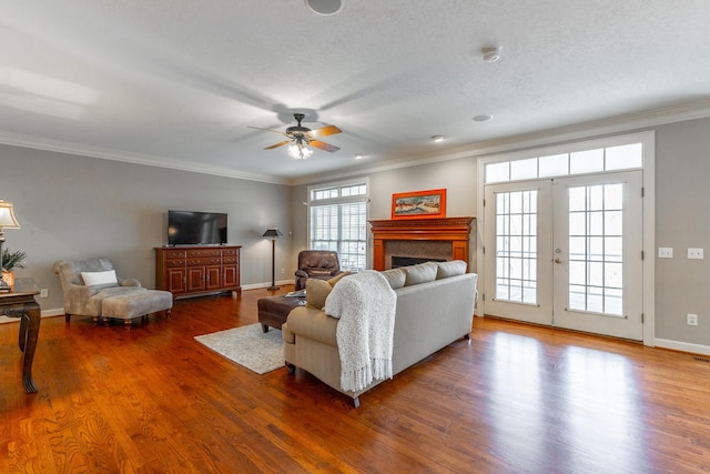 living area featuring baseboards, a ceiling fan, wood finished floors, and a fireplace