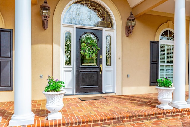 property entrance featuring a porch and stucco siding