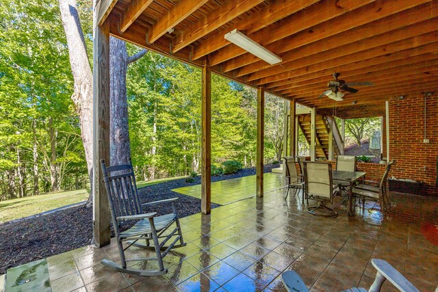 view of patio with outdoor dining area, stairs, and ceiling fan