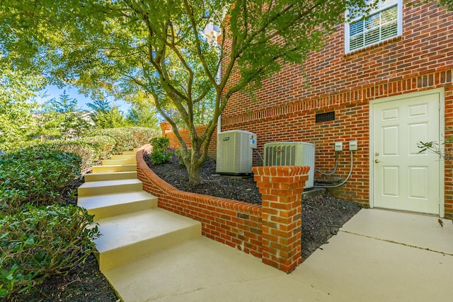 exterior space with stairway, brick siding, and cooling unit