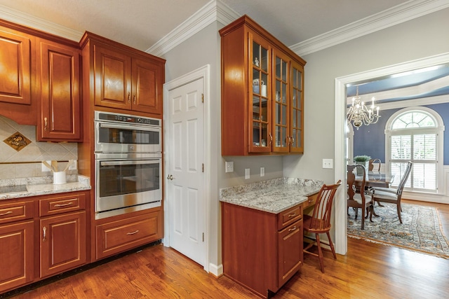 kitchen featuring dark wood-type flooring, crown molding, and stainless steel double oven