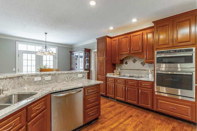 kitchen with dark wood finished floors, ornamental molding, a chandelier, tasteful backsplash, and appliances with stainless steel finishes