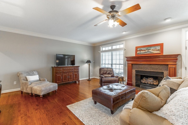living area featuring a ceiling fan, crown molding, a fireplace, baseboards, and dark wood-style flooring