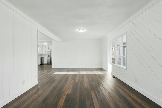 unfurnished living room featuring baseboards, dark wood-type flooring, and crown molding