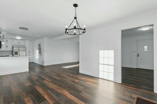 unfurnished living room featuring dark wood finished floors, baseboards, an inviting chandelier, visible vents, and crown molding