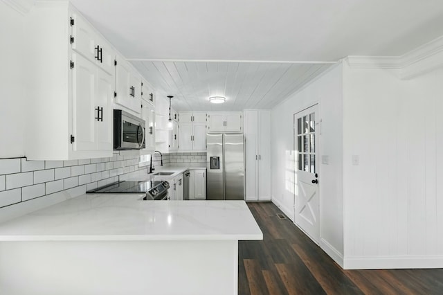 kitchen featuring backsplash, stainless steel appliances, light countertops, dark wood finished floors, and a peninsula