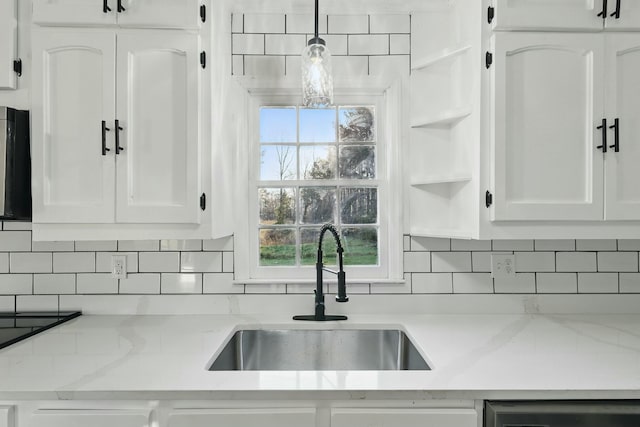kitchen featuring dishwasher, white cabinets, backsplash, and a sink
