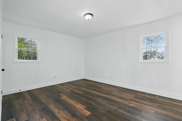 spare room with baseboards, visible vents, a wealth of natural light, and dark wood finished floors