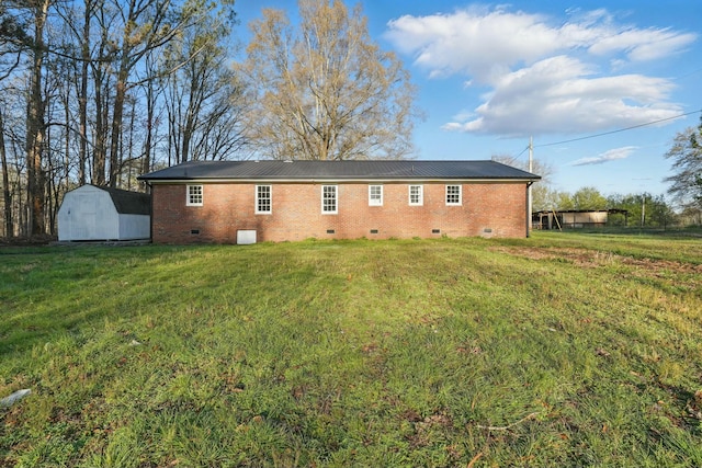 back of house featuring crawl space, a storage shed, a yard, and brick siding