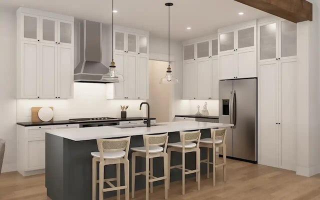 kitchen featuring stainless steel refrigerator with ice dispenser, wall chimney exhaust hood, a sink, light wood-type flooring, and a center island with sink