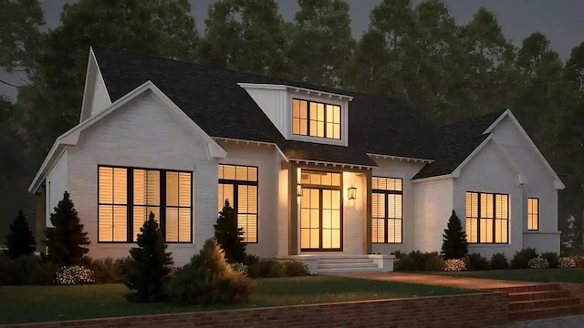 rear view of house with a shingled roof, stucco siding, and a yard
