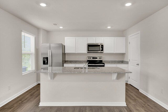 kitchen with white cabinets, visible vents, a kitchen island with sink, stainless steel appliances, and a sink