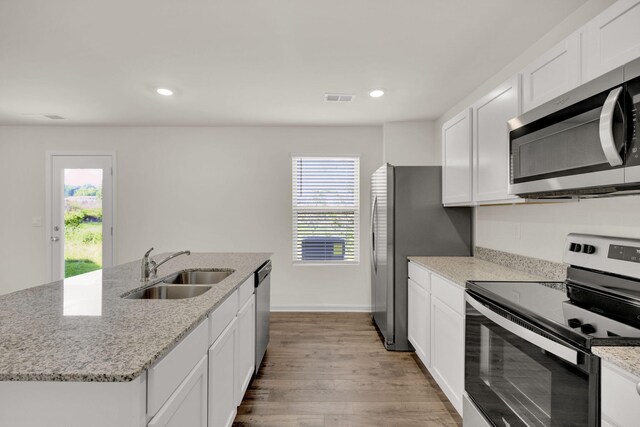 kitchen with white cabinets, visible vents, appliances with stainless steel finishes, a sink, and light wood-style floors