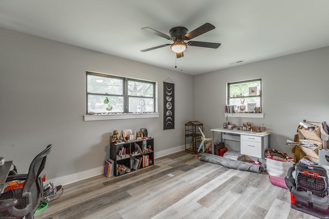 home office featuring light wood-type flooring, ceiling fan, baseboards, and visible vents