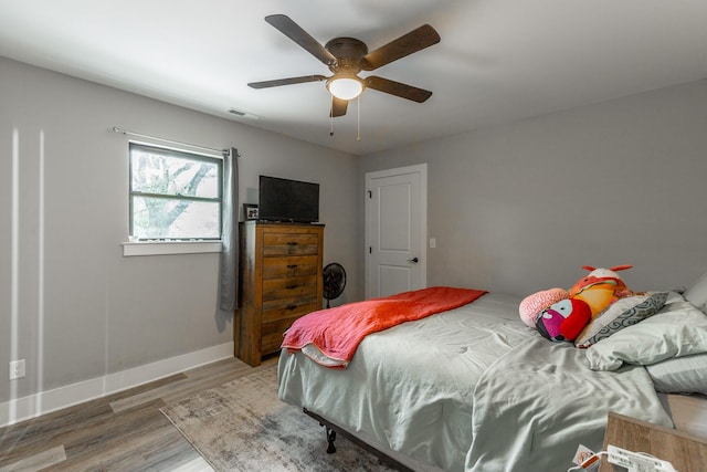 bedroom featuring ceiling fan, visible vents, baseboards, and wood finished floors