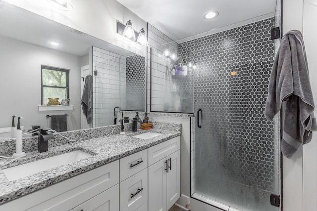 full bath with a sink, a shower stall, double vanity, and recessed lighting