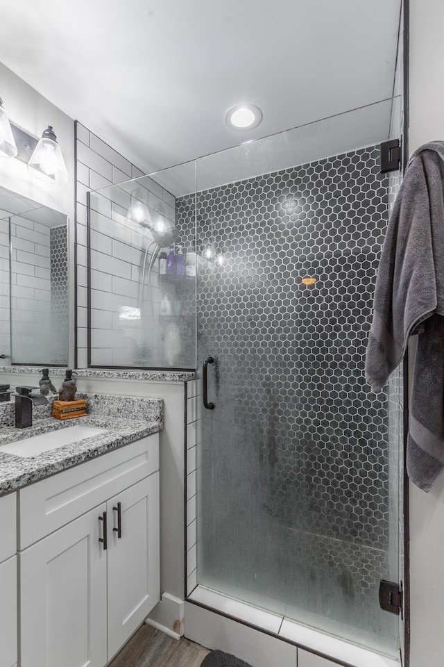 bathroom featuring a stall shower, wood finished floors, and vanity