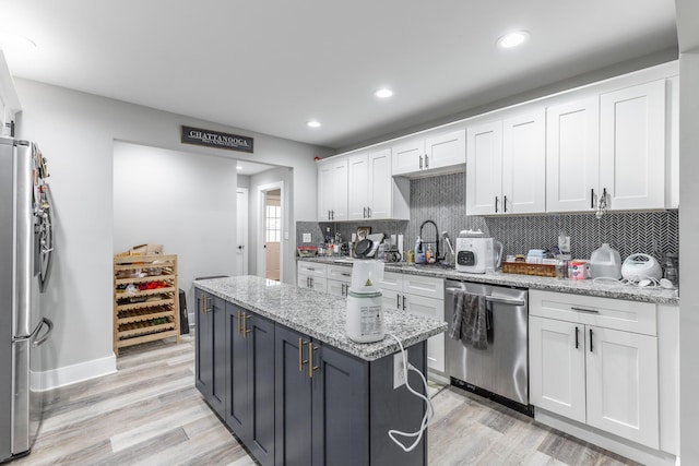 kitchen with tasteful backsplash, light wood-style flooring, white cabinetry, and appliances with stainless steel finishes