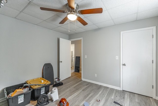 misc room featuring light wood-style flooring, a ceiling fan, and a drop ceiling