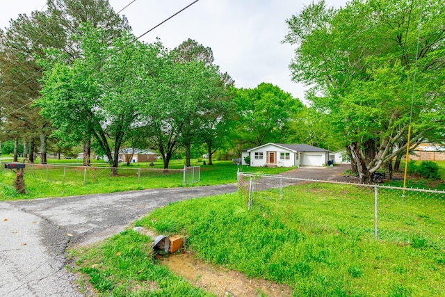 view of front facade with a front lawn, fence, an attached garage, and aphalt driveway