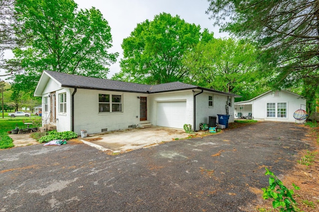 ranch-style house featuring an attached garage, a shingled roof, driveway, and brick siding
