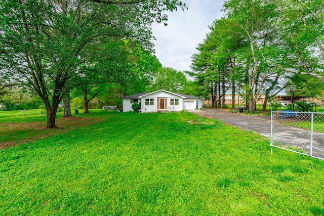 bungalow-style home featuring a front lawn, fence, a garage, and driveway