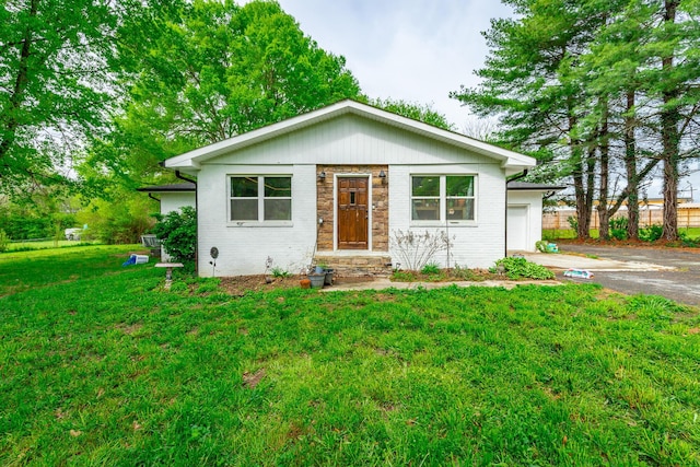 bungalow-style house featuring aphalt driveway, a garage, a front yard, and brick siding