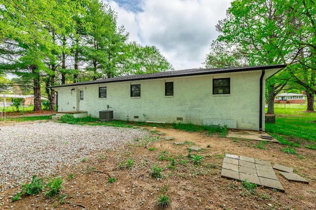 back of property with crawl space, central AC unit, and brick siding