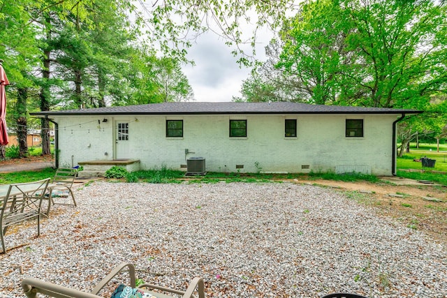 back of property with crawl space, central AC unit, and brick siding
