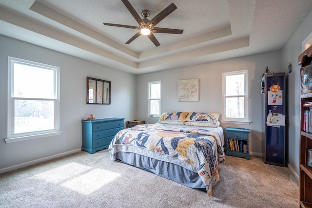carpeted bedroom featuring baseboards, a textured ceiling, and a tray ceiling