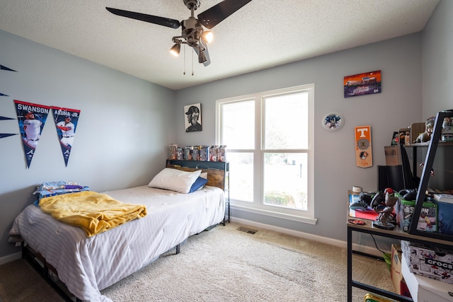 carpeted bedroom featuring baseboards, visible vents, ceiling fan, and a textured ceiling