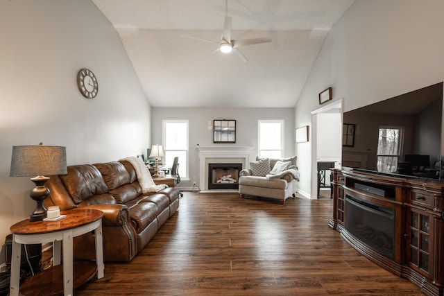 living area featuring dark wood-style flooring, high vaulted ceiling, baseboards, ceiling fan, and a tiled fireplace