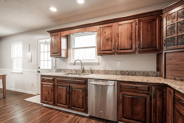 kitchen with a wainscoted wall, a textured ceiling, dark wood-style flooring, a sink, and stainless steel dishwasher