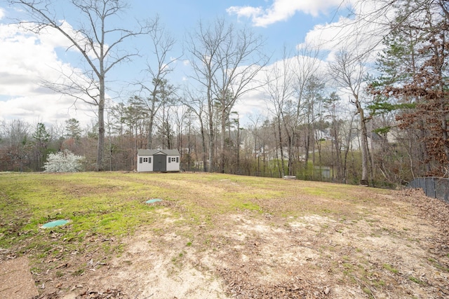 view of yard with an outbuilding, fence, a storage shed, and a forest view