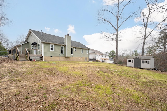 back of house featuring a wooden deck, a chimney, crawl space, an outdoor structure, and a shed
