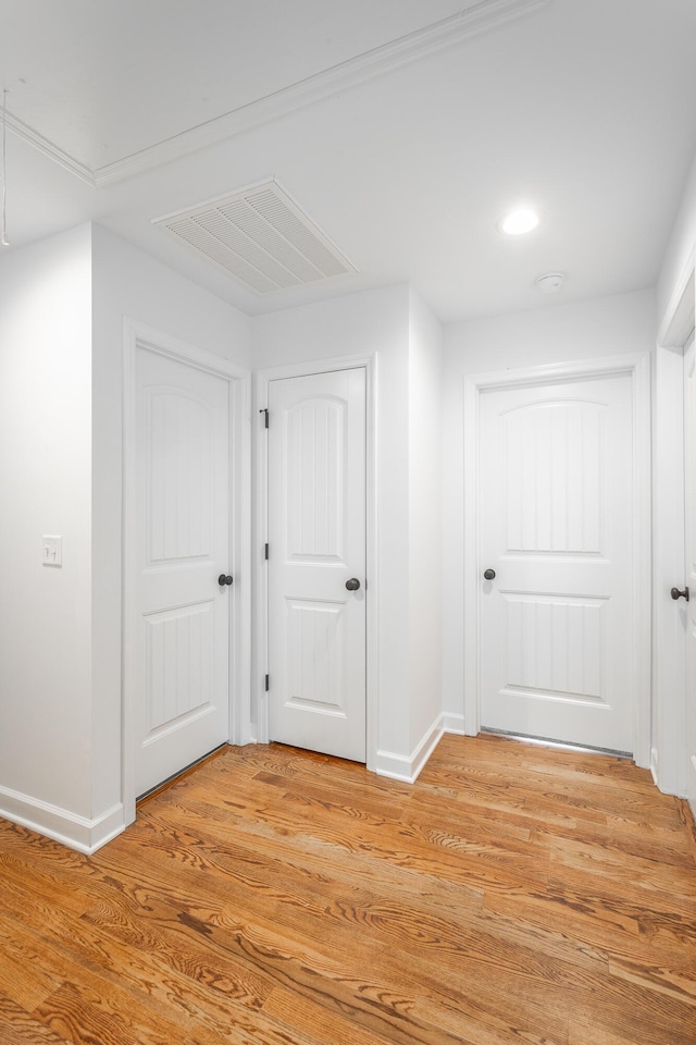 hall featuring attic access, baseboards, light wood-style floors, and visible vents
