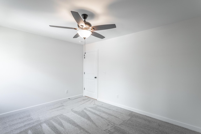 carpeted empty room featuring a ceiling fan and baseboards