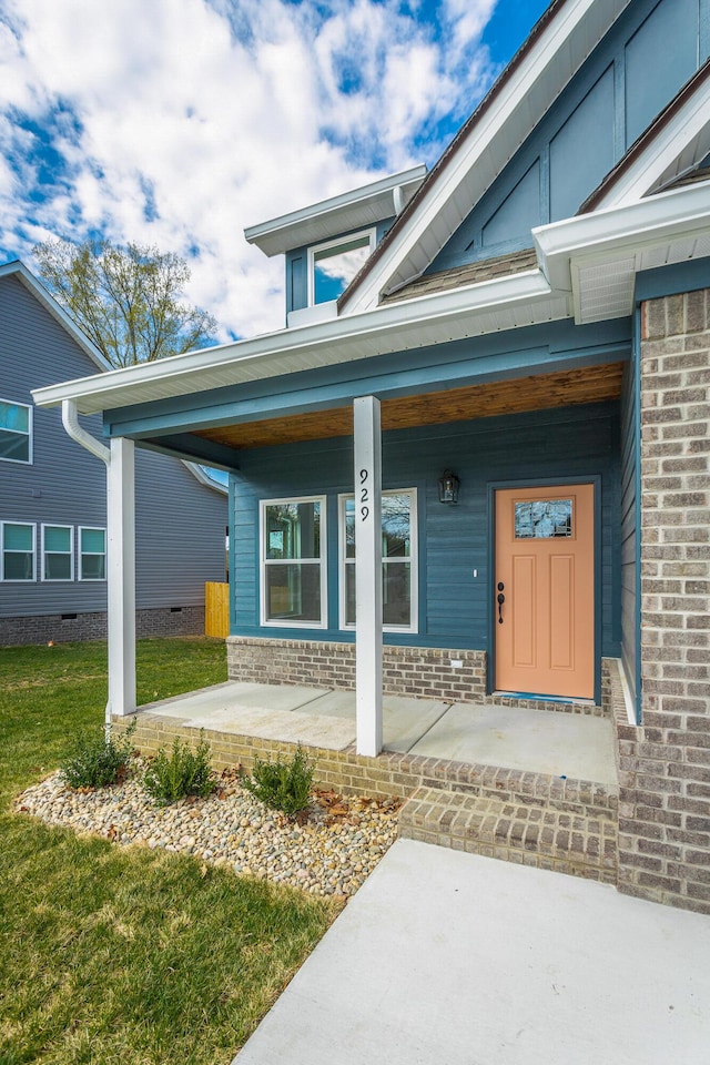 view of exterior entry featuring a porch and a lawn