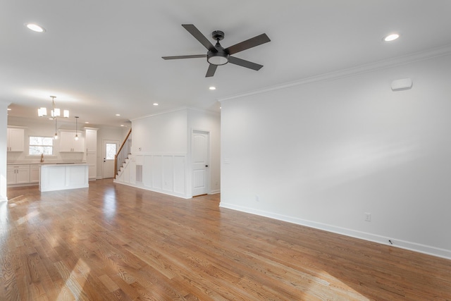 unfurnished living room with ceiling fan, ornamental molding, stairs, and recessed lighting