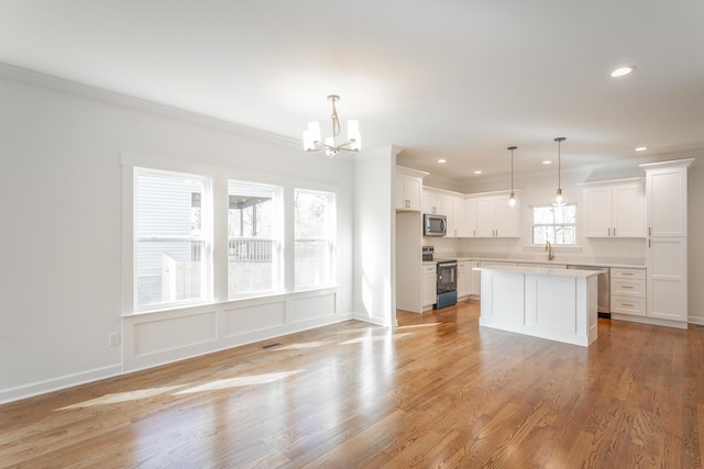 kitchen featuring a sink, range with electric stovetop, an inviting chandelier, light countertops, and stainless steel microwave