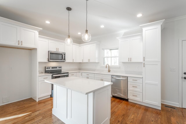 kitchen with white cabinets, stainless steel appliances, a sink, visible vents, and crown molding