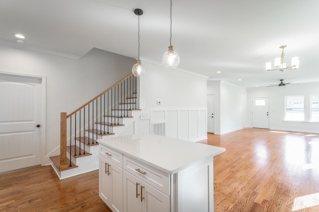 interior space featuring ceiling fan with notable chandelier, ornamental molding, wood finished floors, and recessed lighting