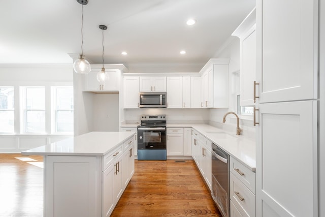 kitchen with light countertops, ornamental molding, a sink, and appliances with stainless steel finishes