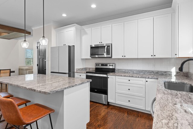 kitchen with a sink, a breakfast bar, stainless steel appliances, white cabinets, and dark wood-type flooring